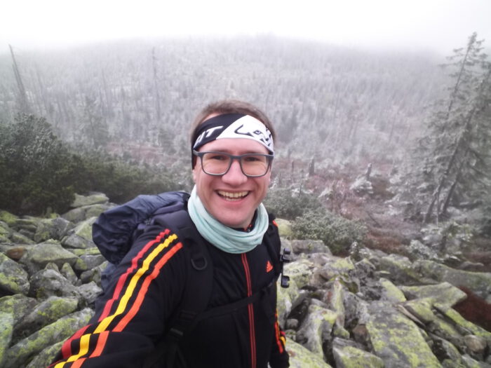 Lächelnder Thorsten macht ein Selfie während einer Wanderung in einer nebligen, frostigen Berglandschaft am Lusen