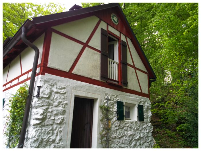 Uriges kleines Fachwerkhaus am Waldrand mit weißem Natursteinsockel und rot-weißem Fachwerk im Giebel bei Oed