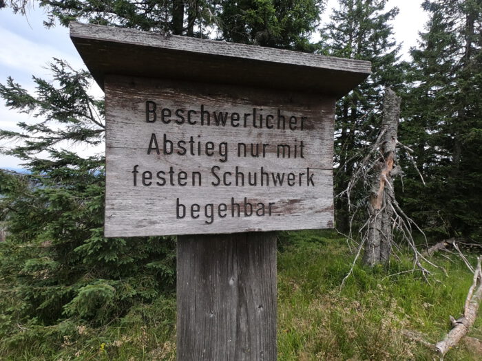 Holzschild mit der Aufschrift: Beschwerlicher Abstieg nur mit festen Schuhwerk begehbar