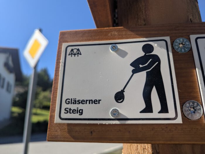 Die Wegmarkierung Gläserner Steig: Schwarzer Glasbläser auf weißem Hintergrund