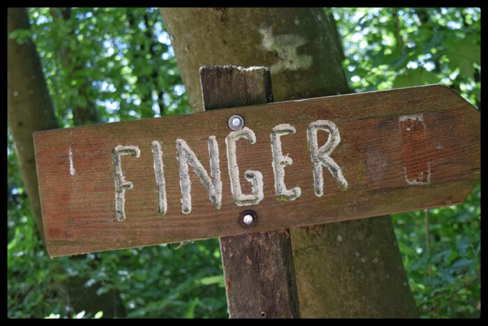 Hölzernes Wegweiserschild mit der Aufschrift FINGER, das nach rechts zeigt