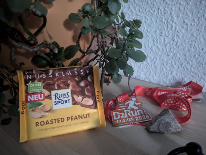 Ritter Sport Schokolade Roasted Peanut neben einer B2Run Finisher 2026 Medaille
