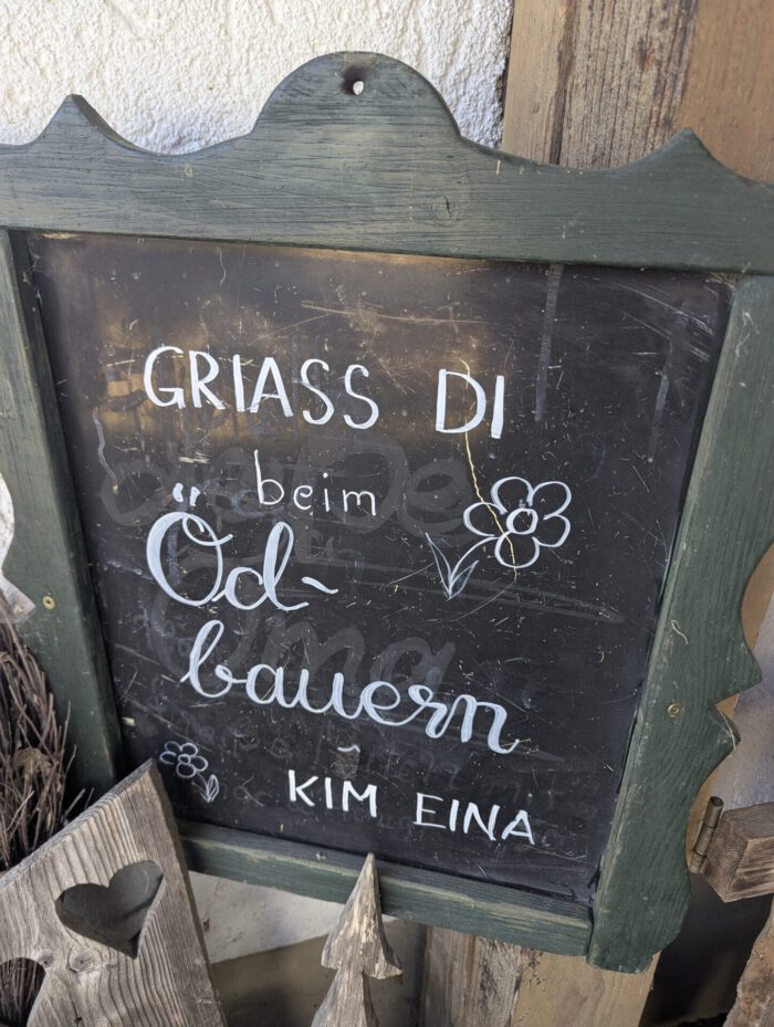 Kreidetafel mit der Aufschrift: Griass di beim Öd-bauern – Kim eina