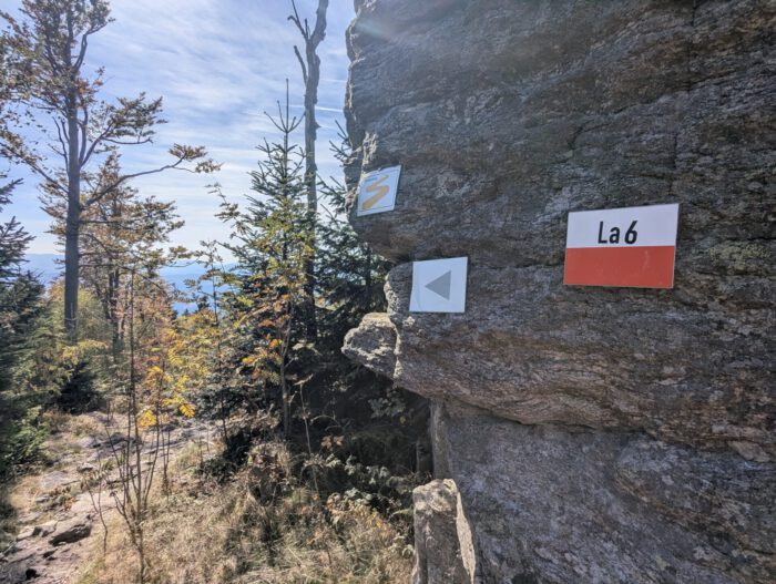 Wanderwegmarkierungen an einer Felswand: Goldsteig-Logo, Pfeil nach links und Schild mit Aufschrift La 6