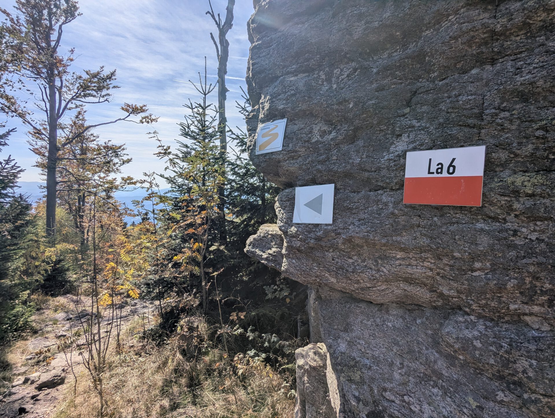 Wanderwegmarkierungen an einer Felswand: Goldsteig-Logo, Pfeil nach links und Schild mit Aufschrift La 6